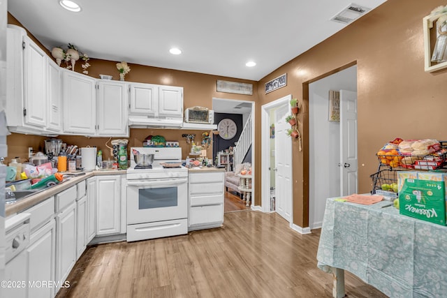 48 Bannard St, Freehold, NJ 07728 - kitchen featuring white range with gas stovetop, under cabinet range hood, light countertops, white cabinetry, and light wood-type flooring