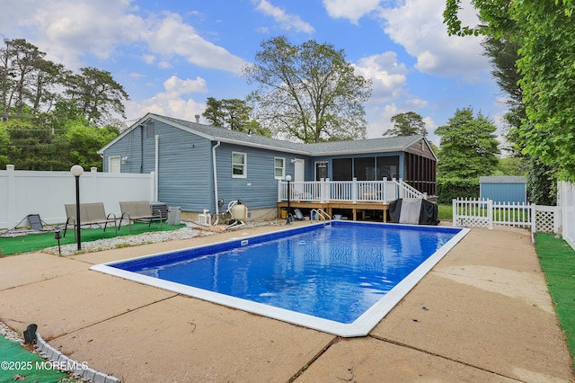 view of swimming pool with a sunroom, a patio area, a fenced backyard, and a wooden deck
