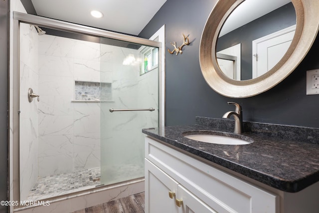bathroom featuring a marble finish shower, wood finished floors, vanity, and recessed lighting