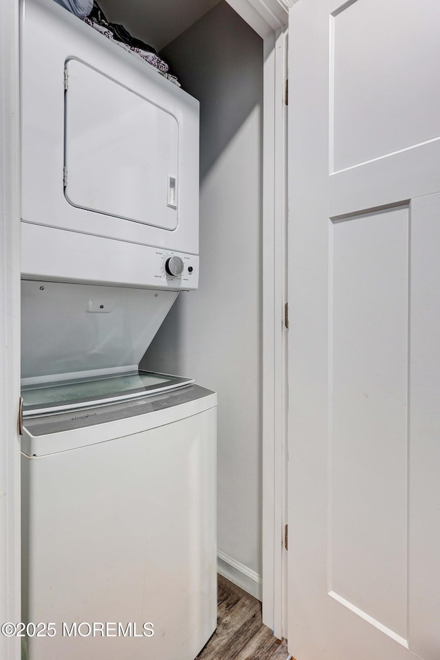laundry area featuring estacked washer and dryer, wood finished floors, and baseboards