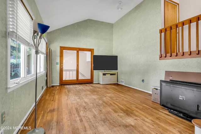 unfurnished living room with high vaulted ceiling, wood finished floors, and baseboards