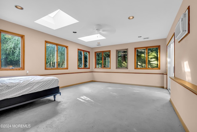 bedroom with a skylight, baseboards, multiple windows, recessed lighting, and a wall mounted air conditioner