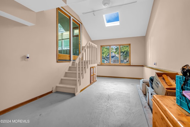 stairs with a skylight, baseboards, vaulted ceiling, and concrete flooring