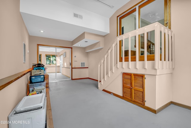 hall with concrete flooring, baseboards, and stairway