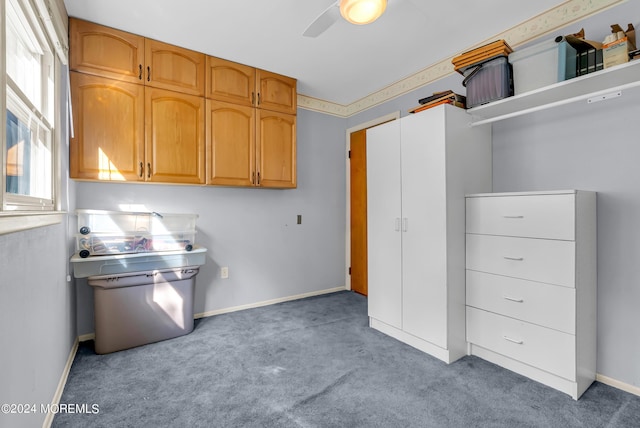 kitchen with light carpet, ceiling fan, baseboards, and brown cabinetry