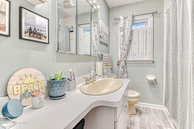 bathroom with wood finished floors, toilet, vanity, and a shower with curtain