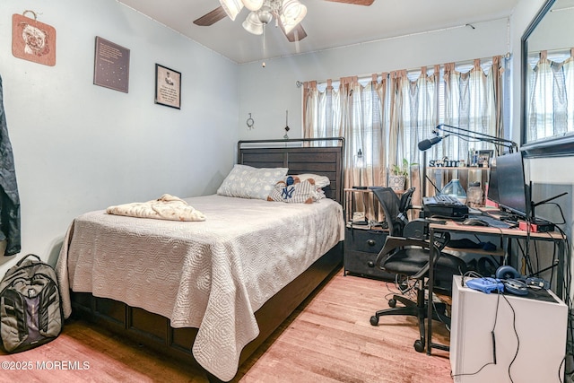 bedroom with wood finished floors, an office area, and a ceiling fan
