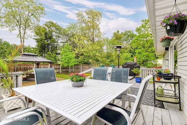 deck featuring outdoor dining space, a fenced backyard, and a gazebo