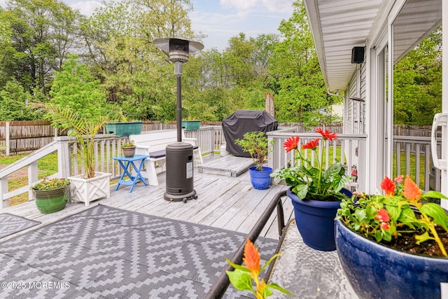 deck featuring a fenced backyard, a grill, and view of scattered trees