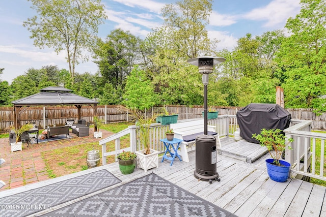wooden terrace with an outdoor hangout area, a gazebo, a fenced backyard, grilling area, and view of wooded area