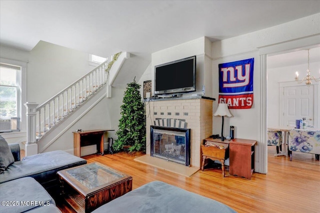 78 Navesink Ave, Highlands, NJ 07732 - living room with stairs, wood finished floors, a brick fireplace, a chandelier, and cooling unit