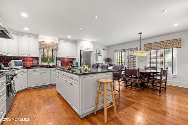 567 Deal Pkwy, Allenhurst, NJ 07711 - kitchen featuring appliances with stainless steel finishes, a kitchen island with sink, white cabinets, a breakfast bar, and recessed lighting