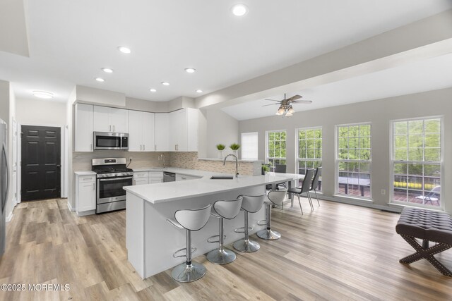 29 Jefferson Ct, Jackson, NJ 08527 - kitchen with appliances with stainless steel finishes, a peninsula, a kitchen breakfast bar, light wood finished floors, and recessed lighting