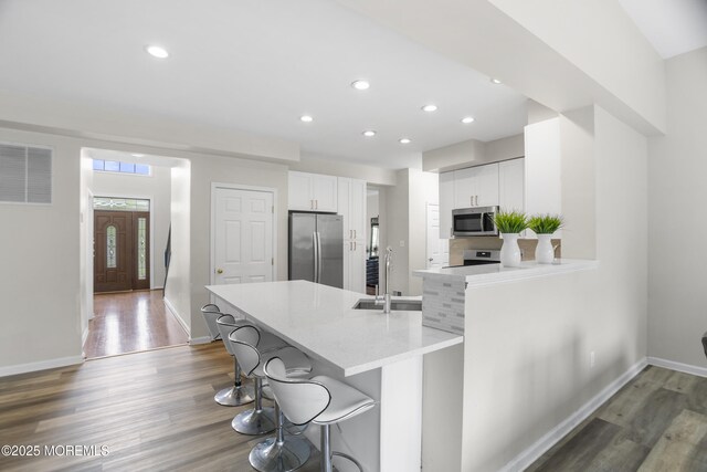 29 Jefferson Ct, Jackson, NJ 08527 - kitchen with stainless steel appliances, a sink, wood finished floors, a kitchen bar, and white cabinetry