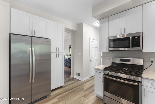 29 Jefferson Ct, Jackson, NJ 08527 - kitchen featuring appliances with stainless steel finishes, light wood-type flooring, light countertops, white cabinets, and backsplash