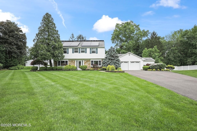 7 Colonial Ct, Manalapan, NJ 07726 - colonial-style house featuring roof mounted solar panels, a garage, and asphalt driveway