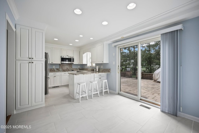 7 Colonial Ct, Manalapan, NJ 07726 - kitchen with appliances with stainless steel finishes, a peninsula, a breakfast bar area, white cabinets, and crown molding