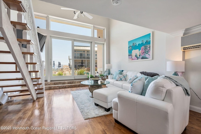 living area with wood finished floors, an AC wall unit, a ceiling fan, stairs, and a view of city