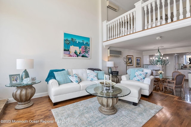 living room featuring wood finished floors, a wall mounted air conditioner, a chandelier, an AC wall unit, and ornamental molding
