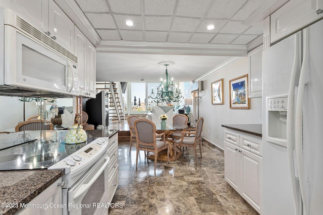 kitchen with white appliances, crown molding, white cabinets, a chandelier, and dark stone counters