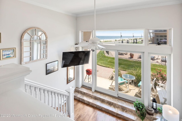 staircase featuring wood finished floors, crown molding, and a ceiling fan