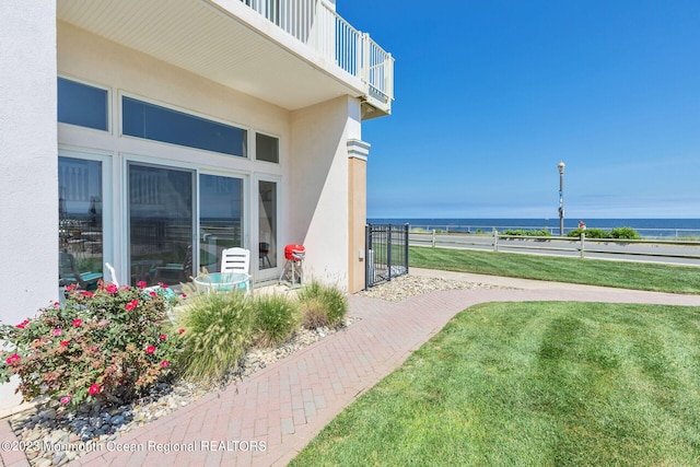 view of side of property featuring a balcony, a water view, and stucco siding