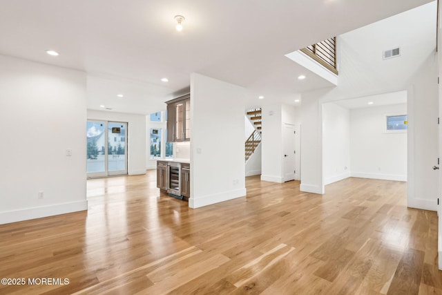 1 Foggia Way, Oceanport, NJ 07757 - unfurnished living room with stairway, light wood-style flooring, baseboards, a dry bar, and wine cooler