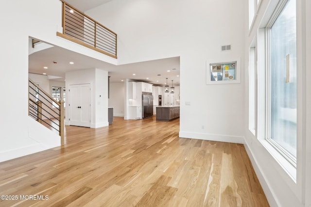 1 Foggia Way, Oceanport, NJ 07757 - unfurnished living room featuring a towering ceiling, light wood-style flooring, stairway, baseboards, and healthy amount of natural light