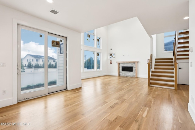 unfurnished living room with stairway, light wood-style floors, a fireplace, recessed lighting, and baseboards