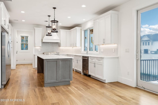 kitchen featuring premium range hood, appliances with stainless steel finishes, tasteful backsplash, a kitchen island, and recessed lighting