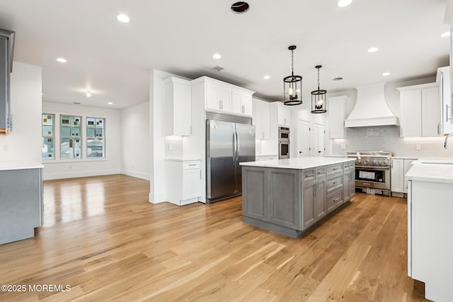 kitchen featuring custom exhaust hood, high quality appliances, gray cabinetry, a center island, and a sink