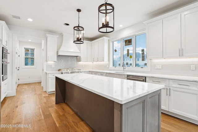 kitchen featuring premium range hood, a sink, tasteful backsplash, stainless steel appliances, and white cabinetry