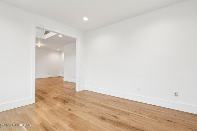 empty room with light wood-style flooring, baseboards, and recessed lighting