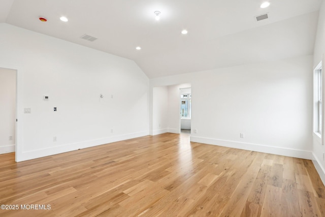 empty room with vaulted ceiling, light wood-type flooring, baseboards, and recessed lighting