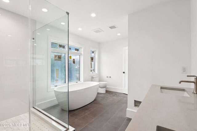 full bath featuring a sink, a soaking tub, a walk in shower, recessed lighting, and toilet