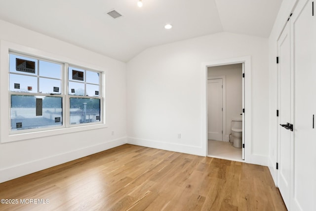 empty room with vaulted ceiling, light wood-style floors, and baseboards