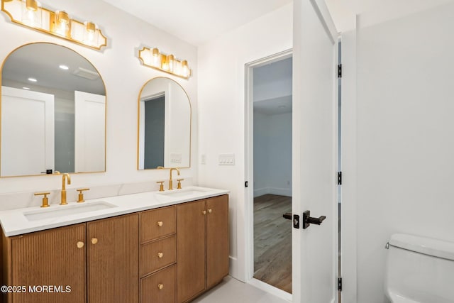full bathroom featuring toilet, double vanity, and wood finished floors