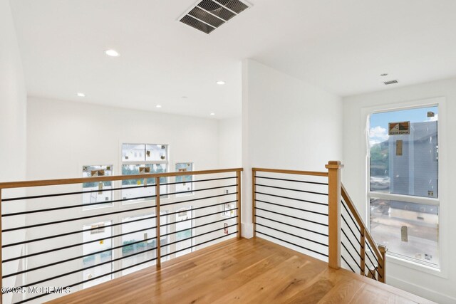 hallway with an upstairs landing, recessed lighting, and wood finished floors
