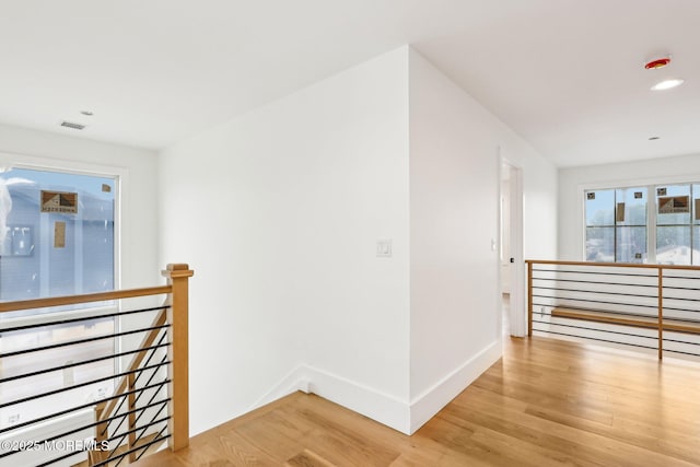 hall with an upstairs landing, light wood finished floors, baseboards, and recessed lighting