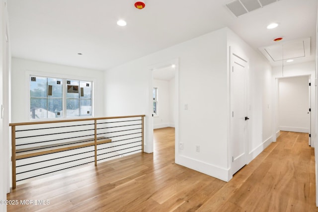 hallway with attic access, light wood-type flooring, baseboards, recessed lighting, and an upstairs landing
