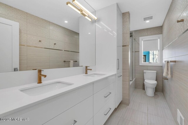 369 Norwood Ave, Long Branch, NJ 07740 - full bath with tile walls, tile patterned floors, toilet, double vanity, and combined bath / shower with glass door
