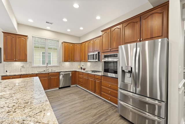 6 Beth Page Dr, Monroe, NJ 08831 - kitchen with appliances with stainless steel finishes, a sink, light stone countertops, light wood-type flooring, and decorative backsplash