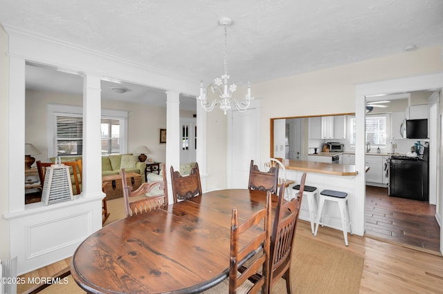 400 W Lake Ave, Bay Head, NJ 08742 - dining space featuring decorative columns, light wood-type flooring, a chandelier, and ceiling fan