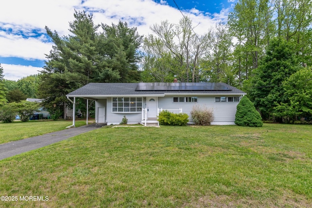 ranch-style home with a front yard, driveway, solar panels, and a carport