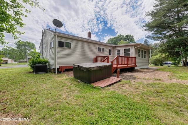 back of property featuring a hot tub, central AC unit, a yard, a chimney, and a wooden deck