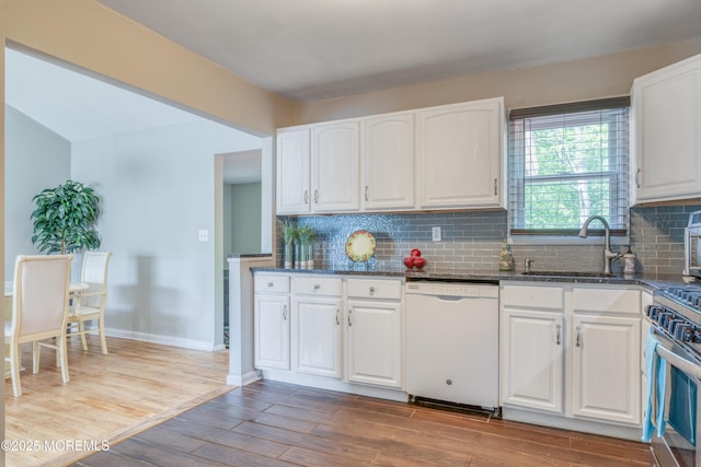 kitchen featuring white dishwasher, a sink, gas stove, and white cabinetry
