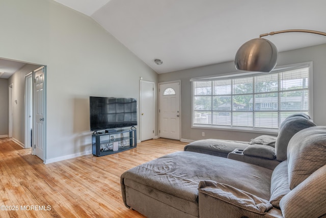 living area with wood finished floors, baseboards, and high vaulted ceiling