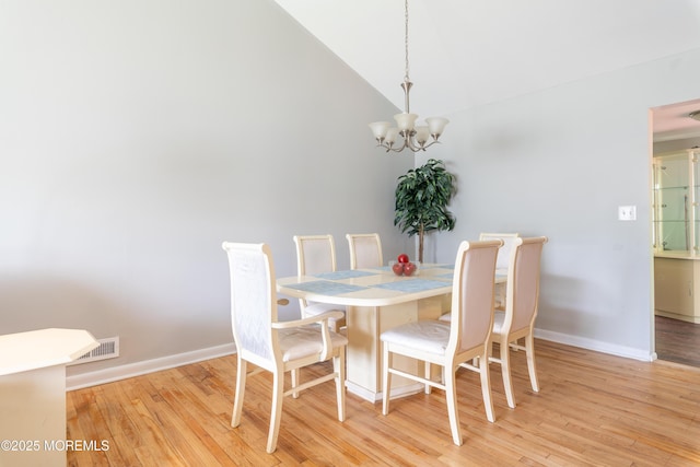 dining area with a chandelier, light wood-type flooring, baseboards, and high vaulted ceiling