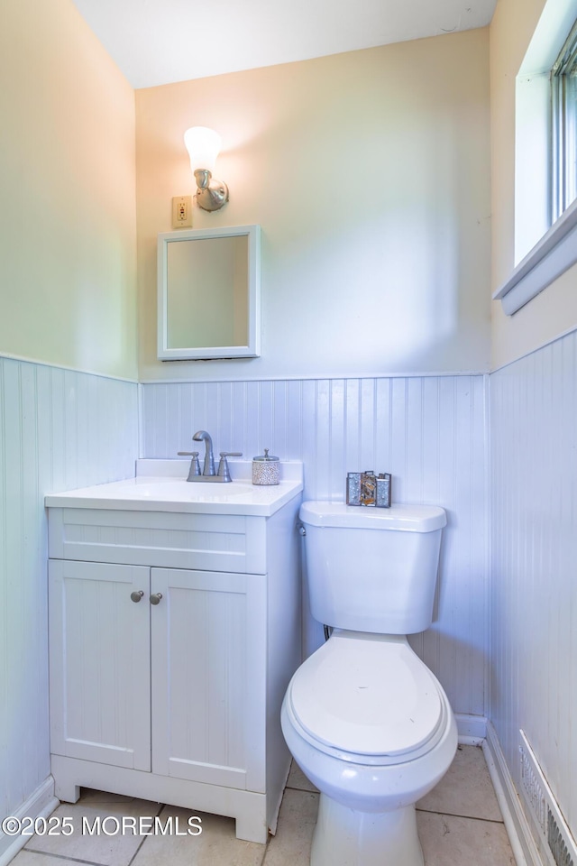 bathroom featuring vanity, a wainscoted wall, toilet, and tile patterned floors