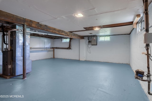 basement with electric panel, heating unit, and concrete block wall